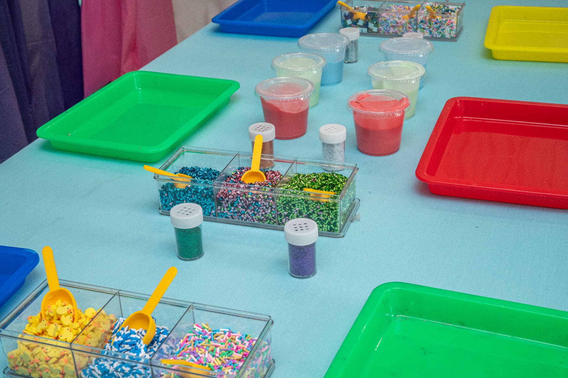 Slime party table with colorful trays and mix-in bar