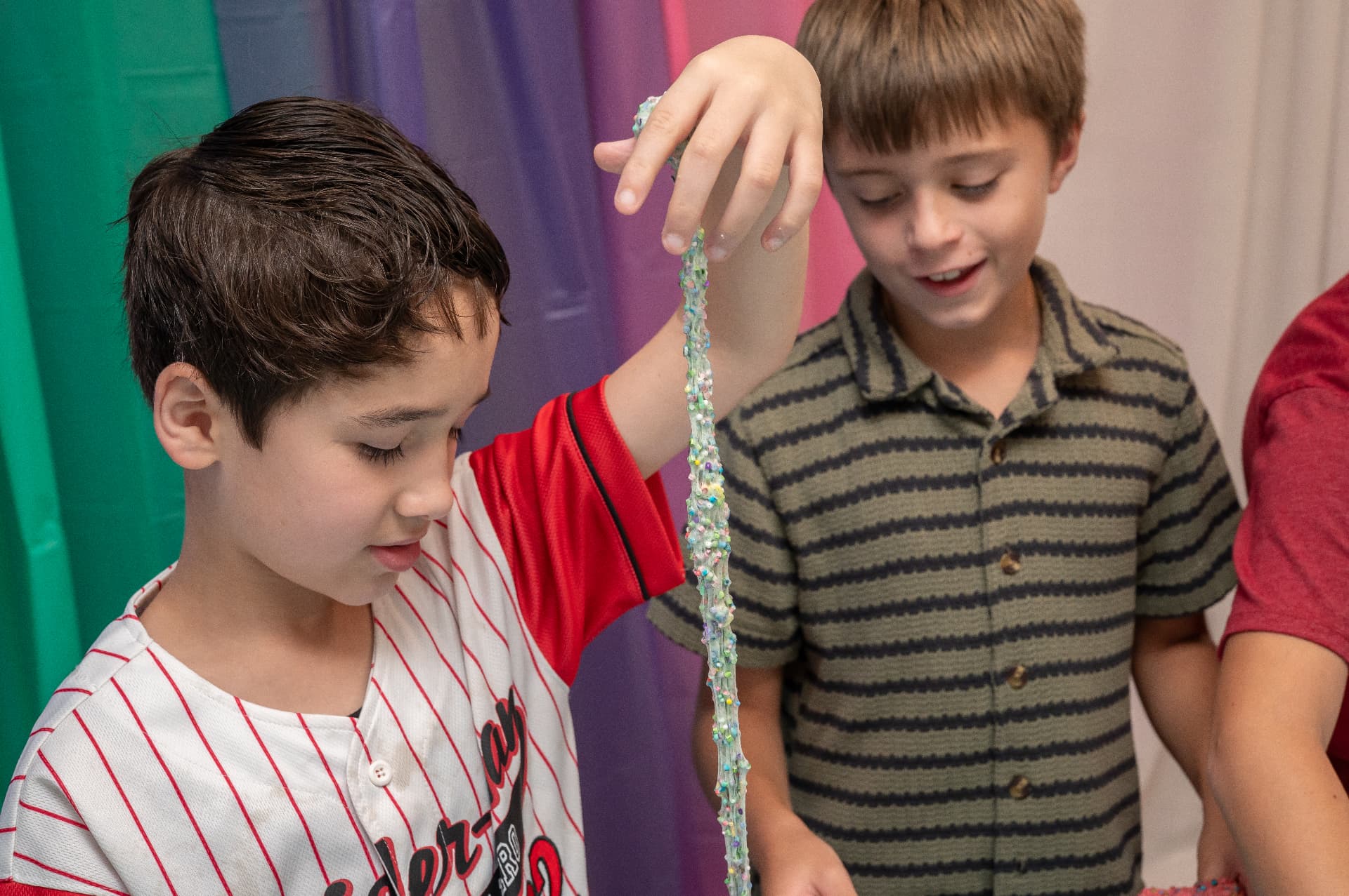 Boy stretching sparkly slime at a slime party